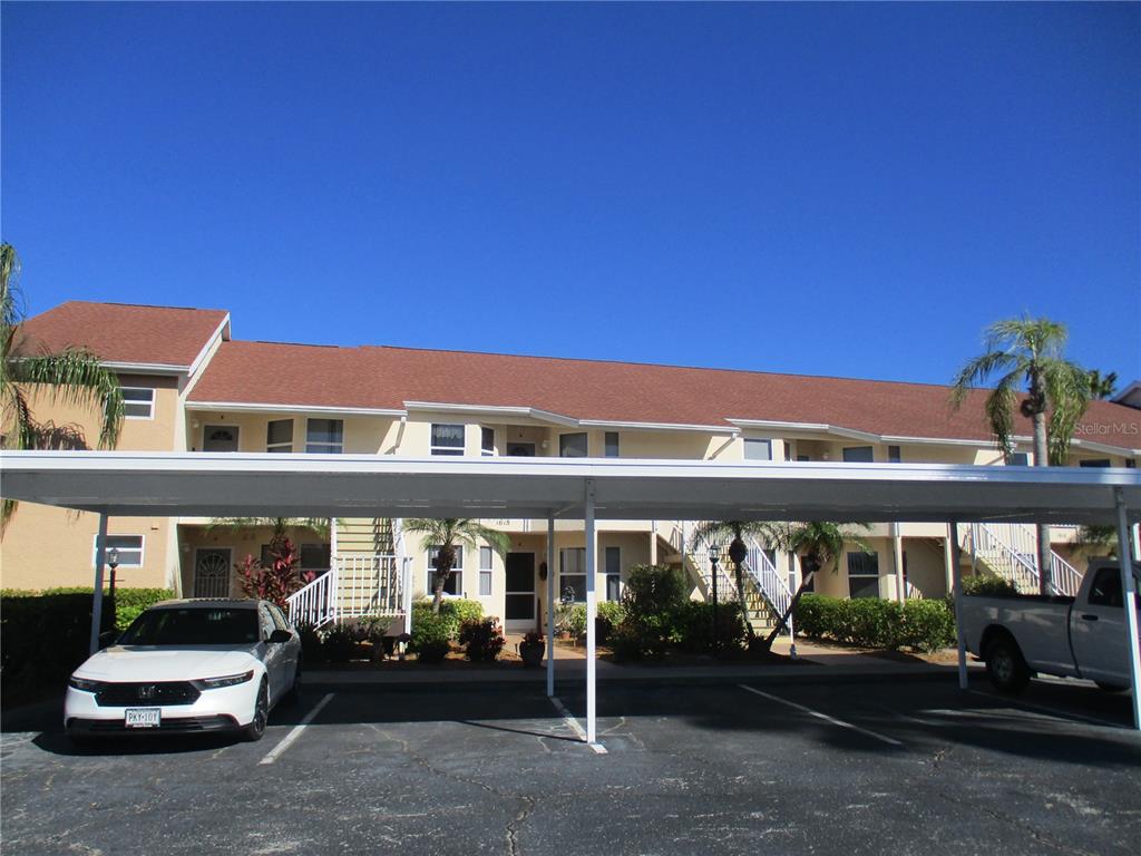 A two-story apartment building with a white metal carport in the foreground — 1620 FAIRWAY TRACE UNIT A, PALMETTO, FL