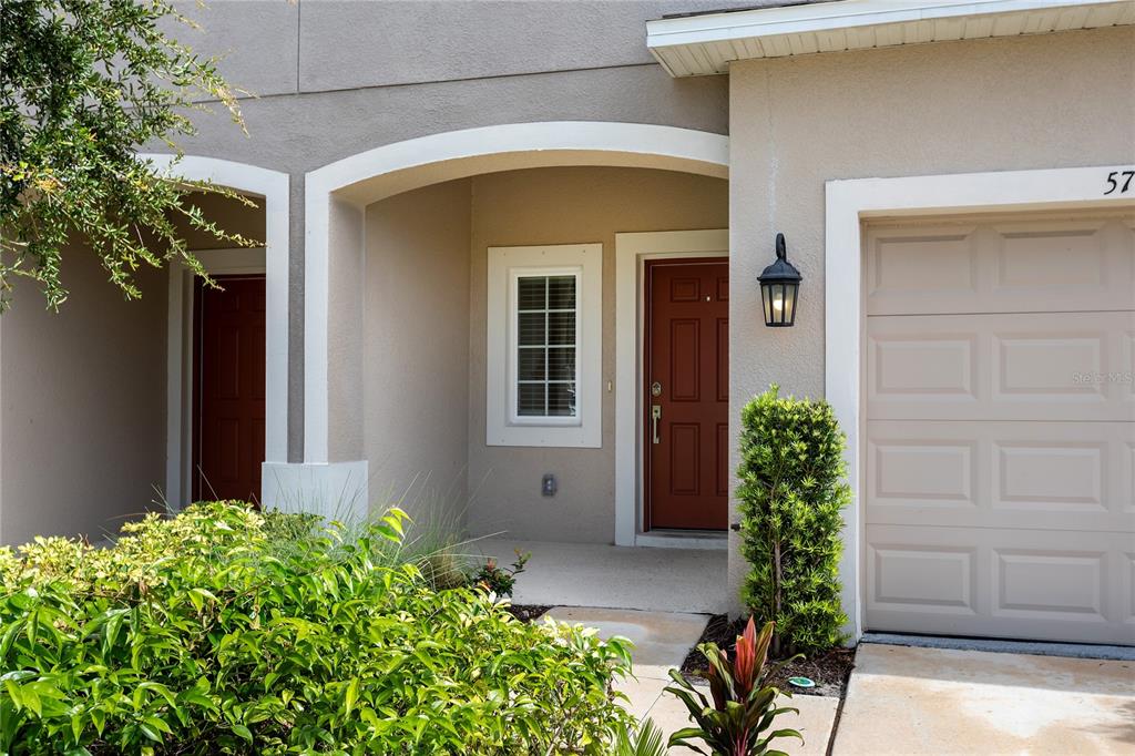 A tiled hallway leads toward a living area with a view of a pond outside — 5780 HAVEN TERRACE, NOKOMIS, FL