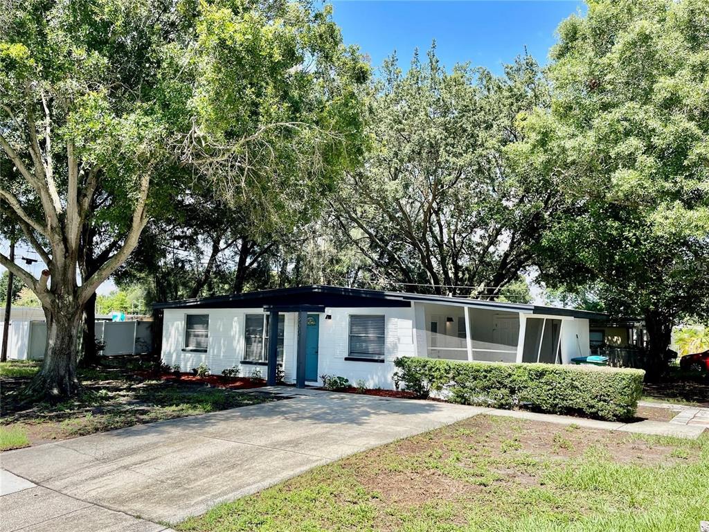 A white single-story house with a flat roof, blue front door, and a screened-in porch — 9001 82ND STREET, SEMINOLE, FL