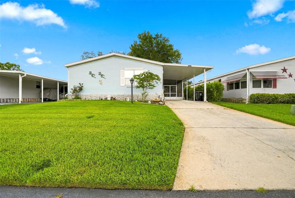 A light blue single-story house with a concrete driveway and an attached carport — 6229 KNOTTY PINE DRIVE SE, WINTER HAVEN, FL