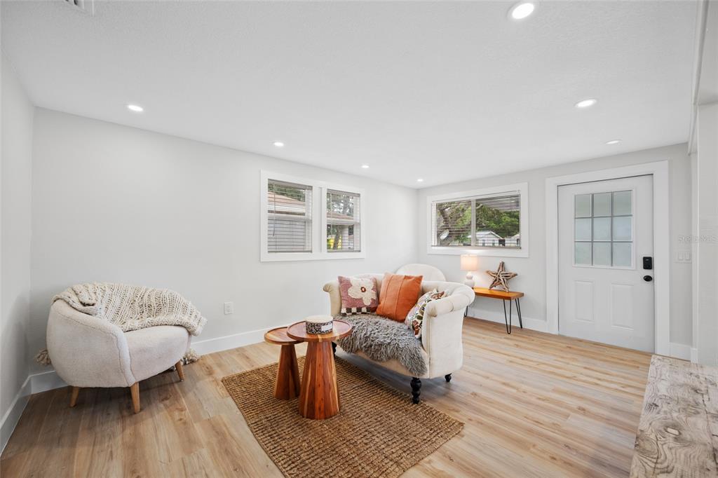 A bright living room features light wood flooring, white walls, and a small seating area — 2547 KINGSTON STREET S, ST PETERSBURG, FL