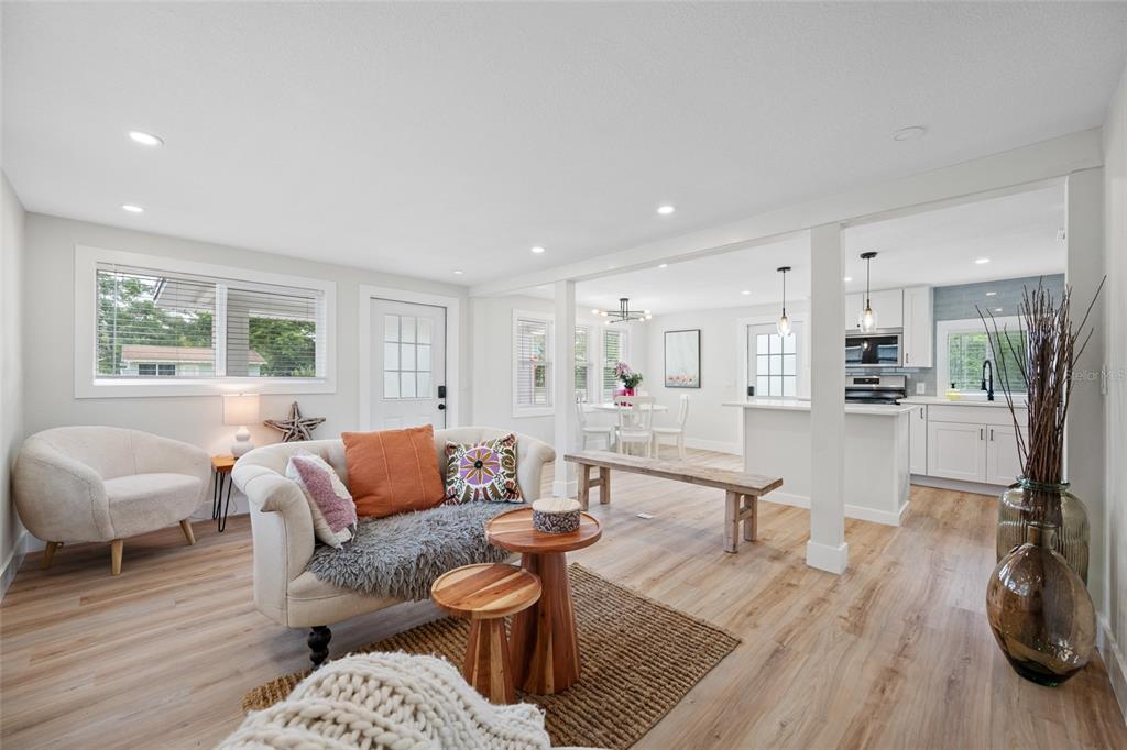 A bright, open-concept living room and kitchen featuring light wood floors and white cabinetry — 2547 KINGSTON STREET S, ST PETERSBURG, FL
