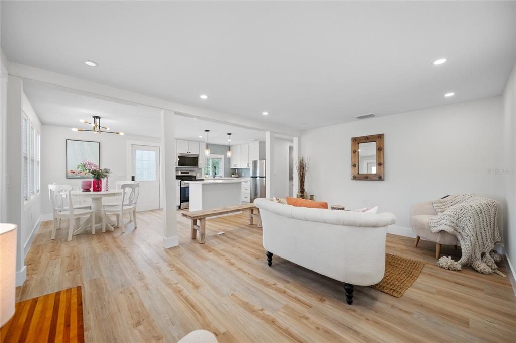An open-concept living and dining area features light wood flooring, white walls, and a kitchen — 2547 KINGSTON STREET S, ST PETERSBURG, FL