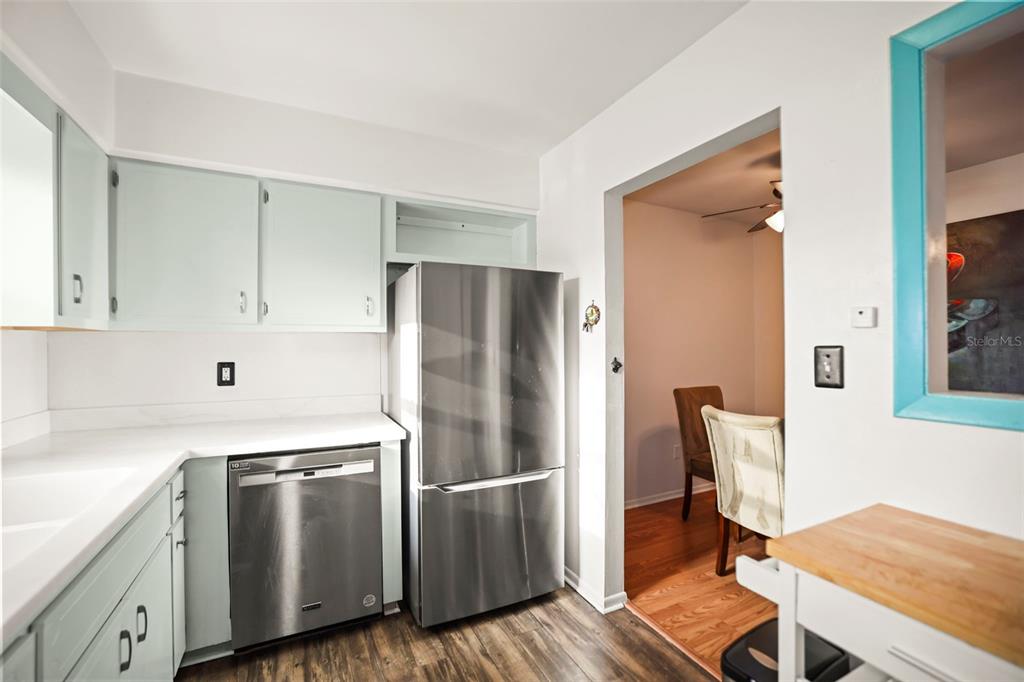 A kitchen with light blue cabinets, stainless steel appliances, and a view into a dining area — 180 SKY LOCH DRIVE W, DUNEDIN, FL