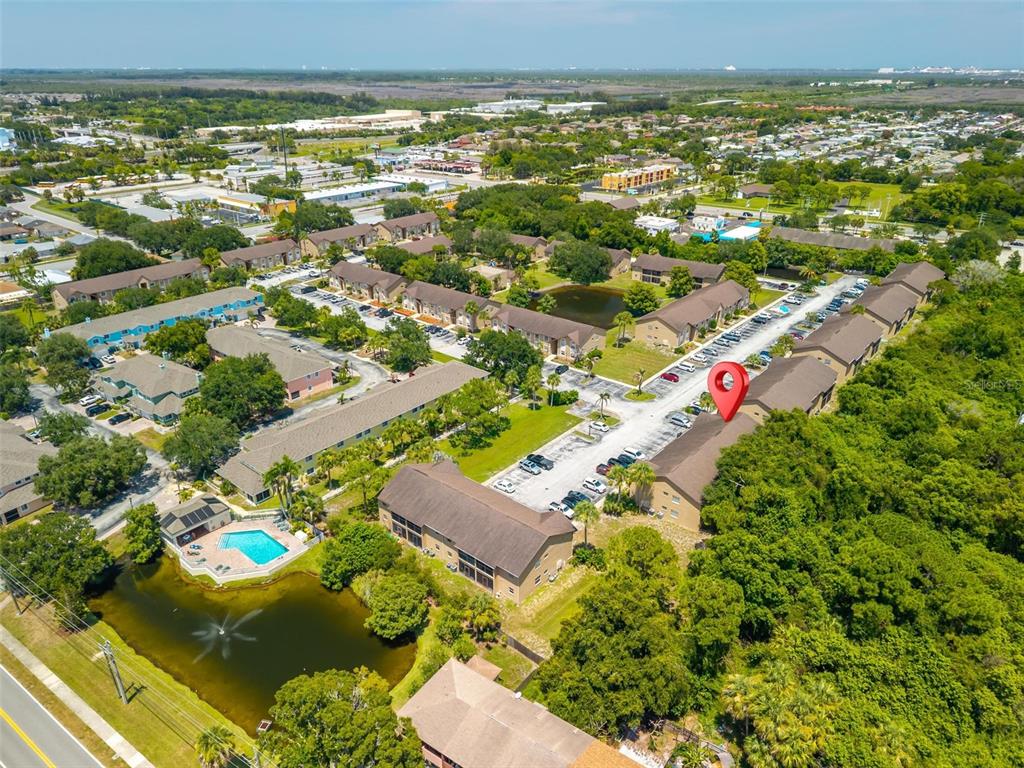An aerial view shows a multi-building apartment complex with a swimming pool and pond — 265 SPRING DR UNIT 1, MERRITT ISLAND, FL