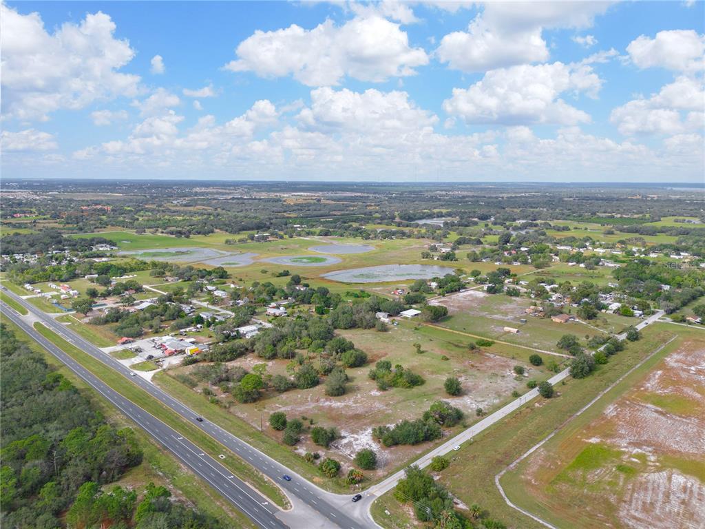 An aerial view shows a rural landscape with a highway, scattered houses, and several ponds — STATE ROAD 60 E, LAKE WALES, FL
