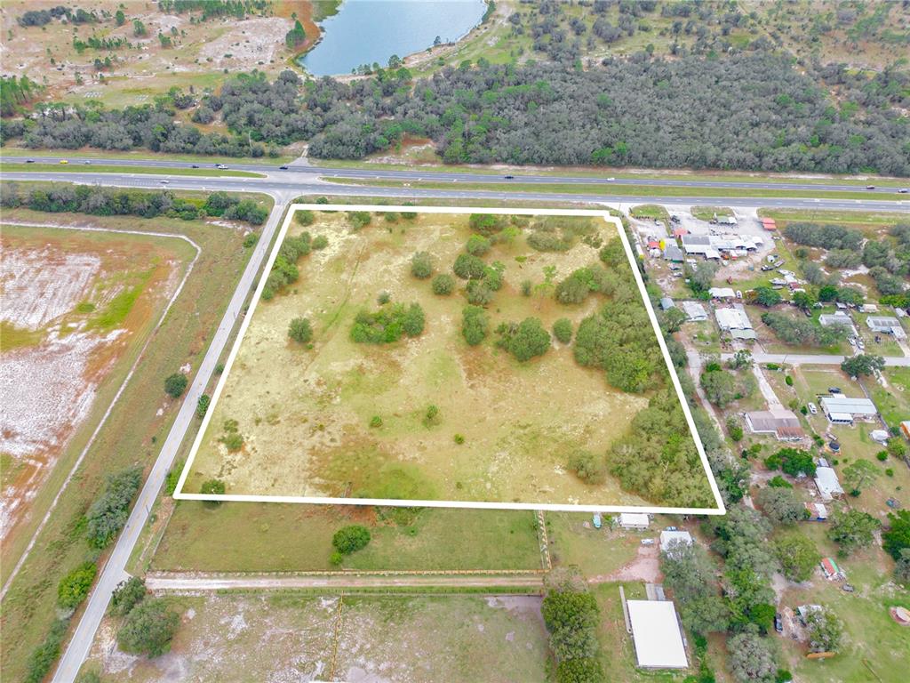 An aerial view shows a rectangular plot of land outlined in white near a highway — STATE ROAD 60 E, LAKE WALES, FL