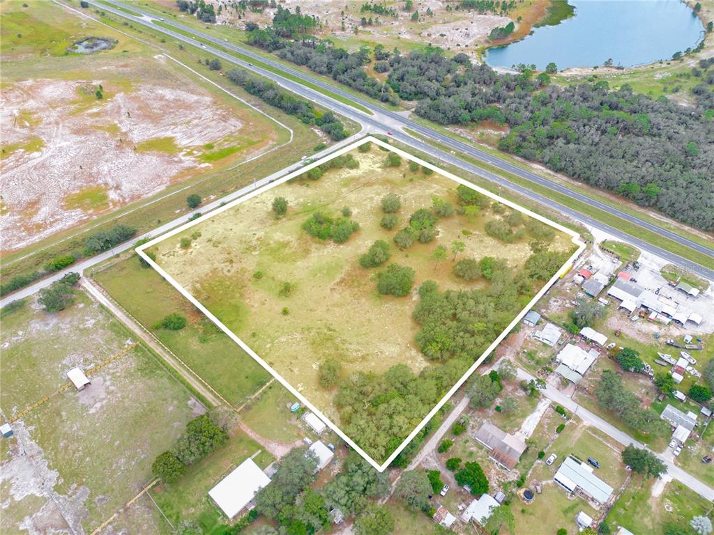 An aerial view shows a large, square, undeveloped plot of land bordered by roads — STATE ROAD 60 E, LAKE WALES, FL