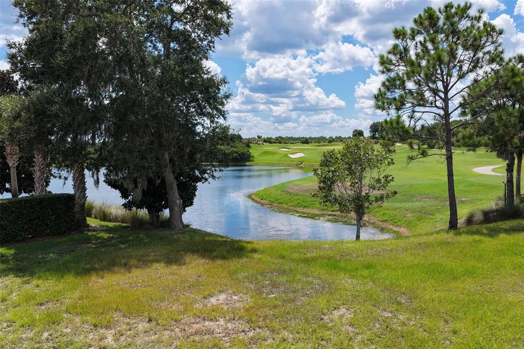 A view of a pond and golf course fairway framed by trees under a cloudy sky — 518 SWEETGUM LANE, PALM COAST, FL