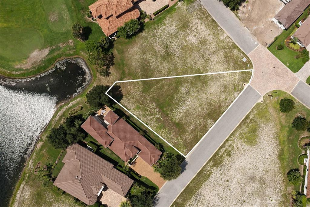 An aerial view shows a vacant, triangular residential lot bordered by a road and pond — 518 SWEETGUM LANE, PALM COAST, FL