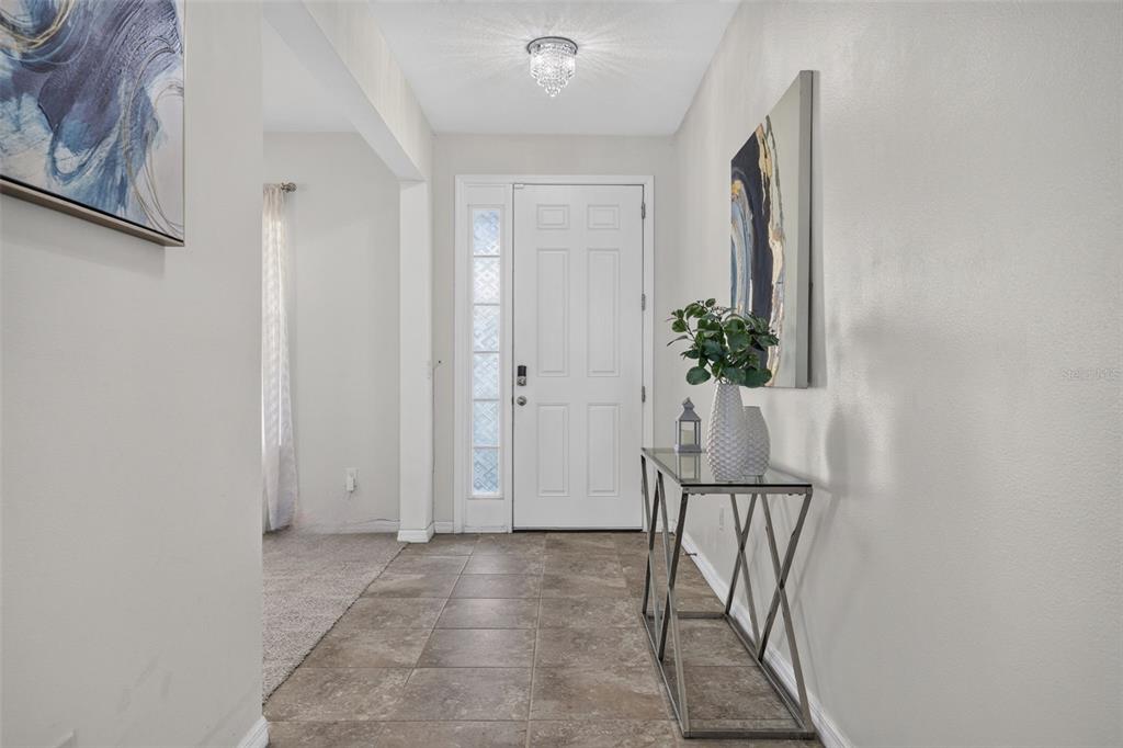 A tiled entryway features a glass-topped console table, a white front door, and wall art — 6541 DEVESTA LOOP, PALMETTO, FL
