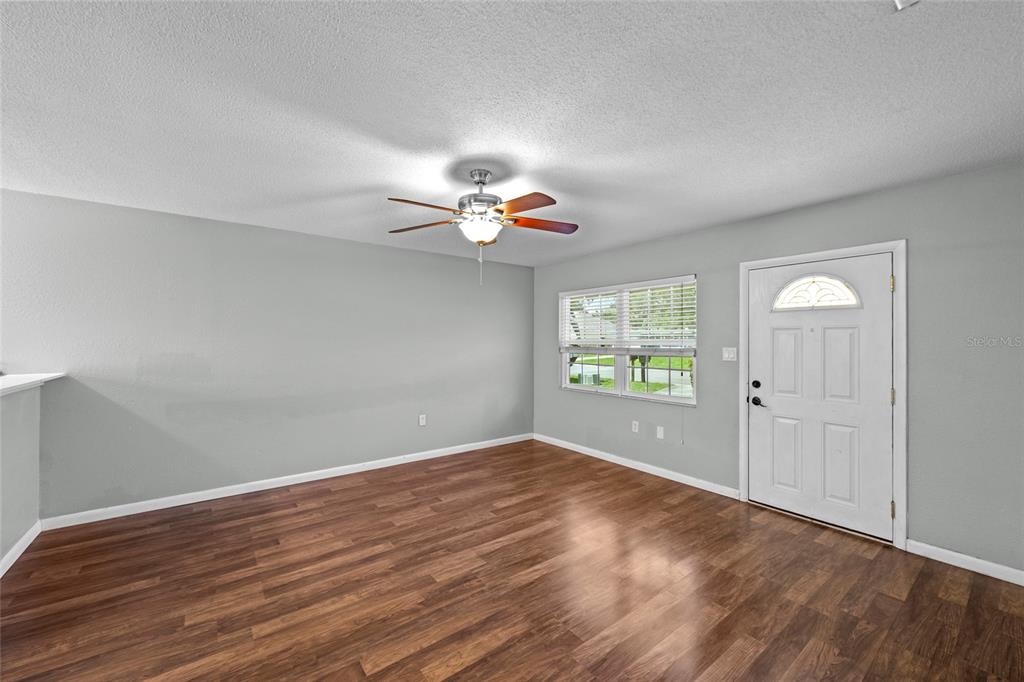 A living room with gray walls, wood-look flooring, a ceiling fan, and a white door — 3909 COLERIDGE PLACE, SARASOTA, FL