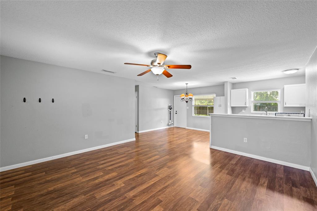 An open-concept living and dining area features wood-look flooring, gray walls, and a ceiling fan — 3909 COLERIDGE PLACE, SARASOTA, FL