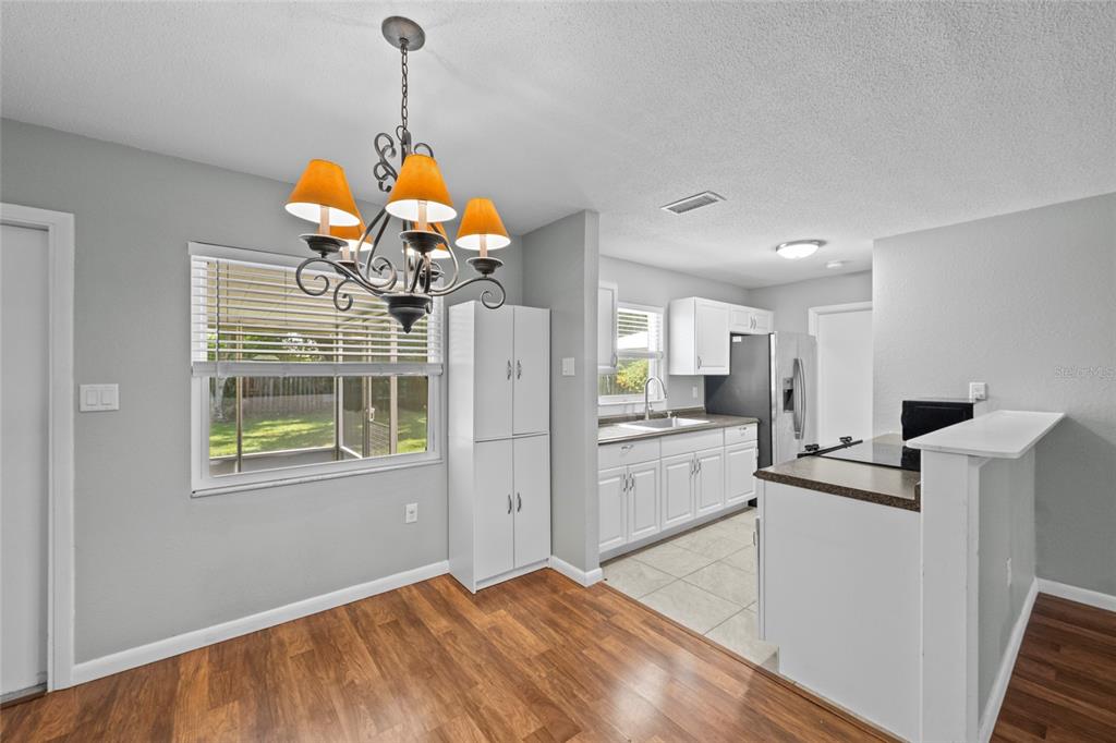 A dining area with wood flooring and a chandelier adjacent to a white kitchen — 3909 COLERIDGE PLACE, SARASOTA, FL