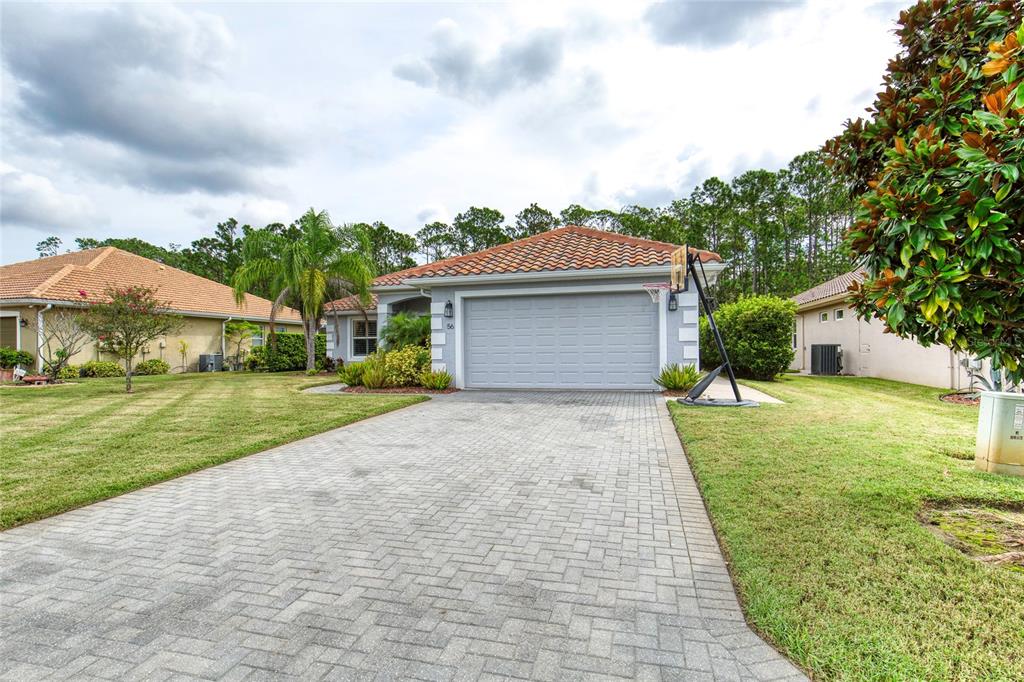 A single-story house with a tiled roof, gray garage door, and a paved driveway — 56 THORNHILL CHASE CIRCLE, ORMOND BEACH, FL