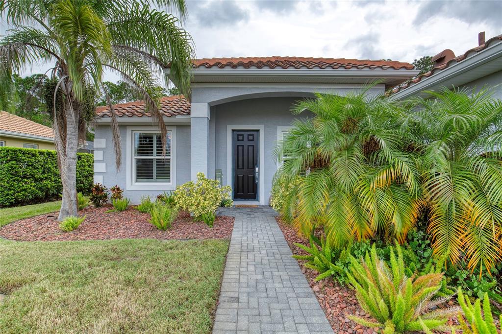 A gray house with a tiled roof, a paved walkway, and landscaping in the front yard — 56 THORNHILL CHASE CIRCLE, ORMOND BEACH, FL