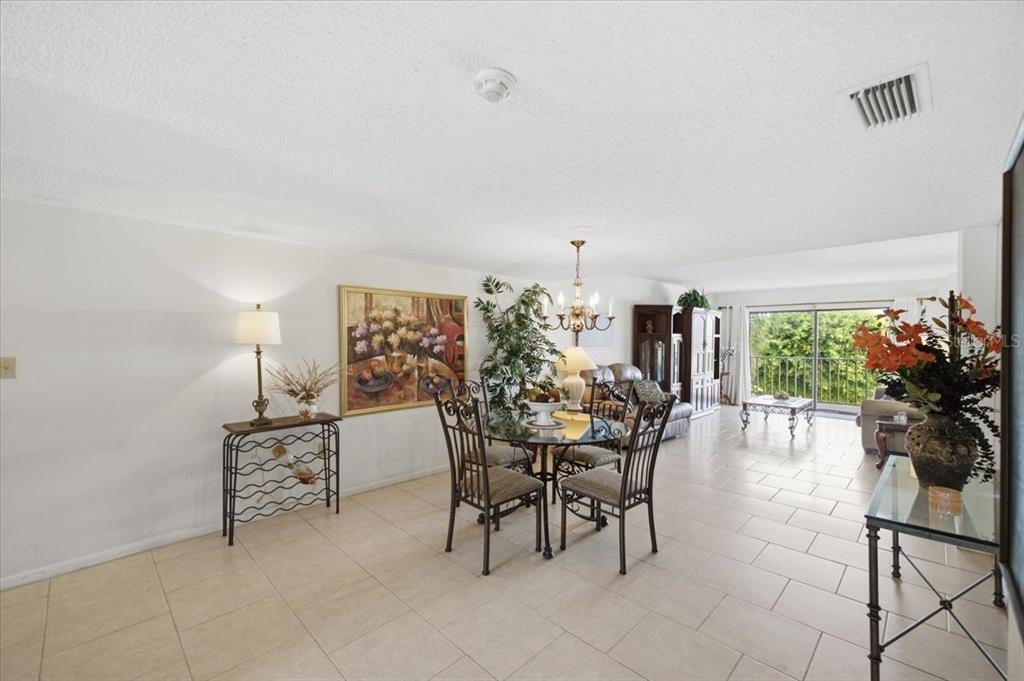 A dining area with a glass table and chairs sits in an open-concept living space — 7050 SUNSET DRIVE S UNIT 216, SOUTH PASADENA, FL