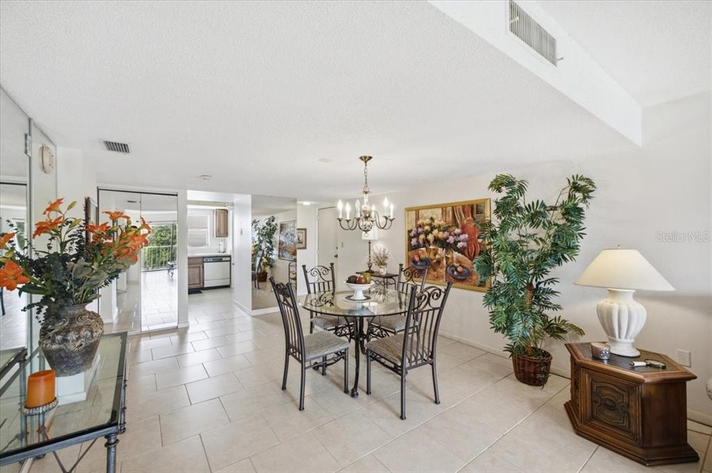 A dining area with a glass table, metal chairs, tile floors, and a chandelier — 7050 SUNSET DRIVE S UNIT 216, SOUTH PASADENA, FL