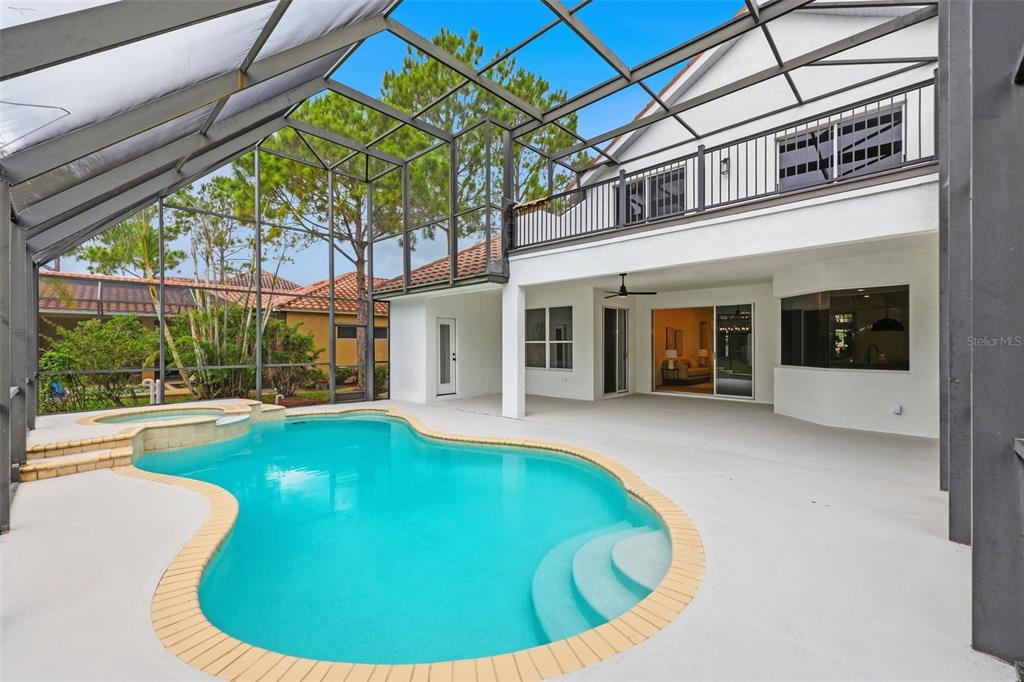 A swimming pool and spa are enclosed within a screened lanai behind a two-story house — 10534 BERMUDA ISLE DRIVE, TAMPA, FL