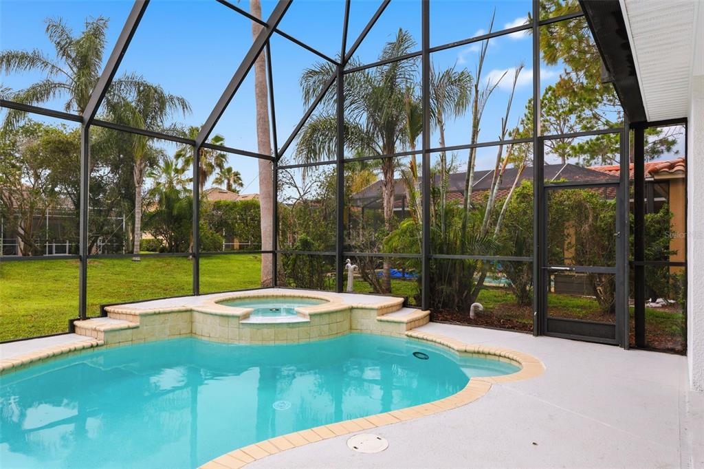A screened-in pool and spa area with light-colored tile coping and a concrete deck — 10534 BERMUDA ISLE DRIVE, TAMPA, FL