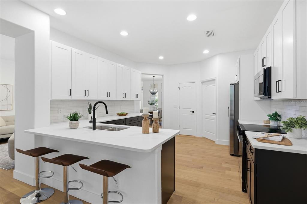 A modern kitchen features white upper cabinets, dark lower cabinets, a white island, and barstools — 10534 BERMUDA ISLE DRIVE, TAMPA, FL
