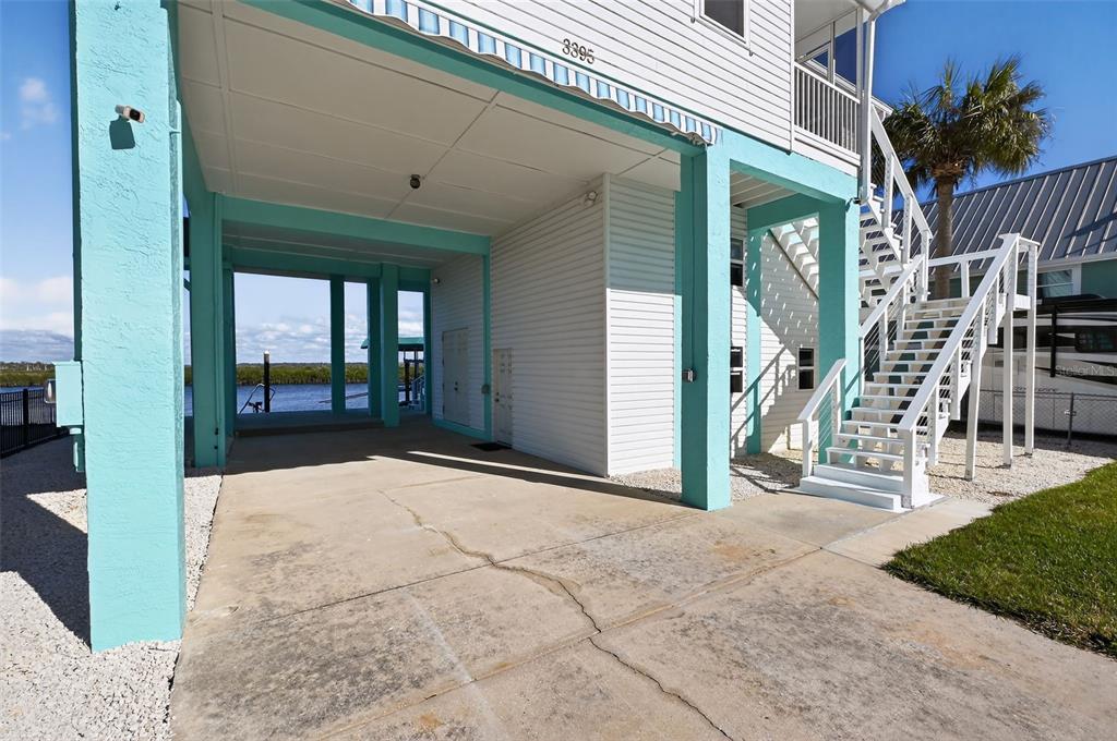 The exterior of a stilt house features a concrete driveway, white siding, and a staircase — 3395 EAGLE NEST DRIVE, HERNANDO BEACH, FL