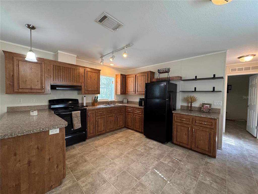 A kitchen features wood cabinets, black appliances, laminate countertops, and tile flooring — 44 KELLY RIDGE ROAD, FROSTPROOF, FL