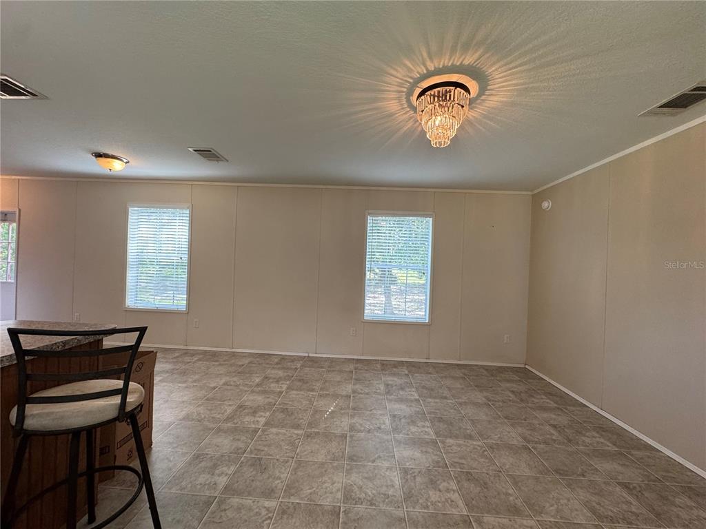 A dining area with tile flooring, two windows, and a crystal chandelier light fixture — 44 KELLY RIDGE ROAD, FROSTPROOF, FL