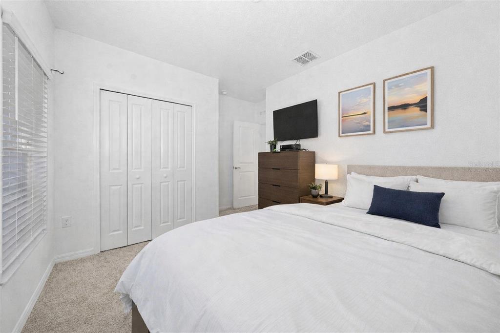 A bedroom features a bed with white bedding, a dark dresser, and a closet — 3977 WILLOWBROOK DRIVE, EDGEWATER, FL