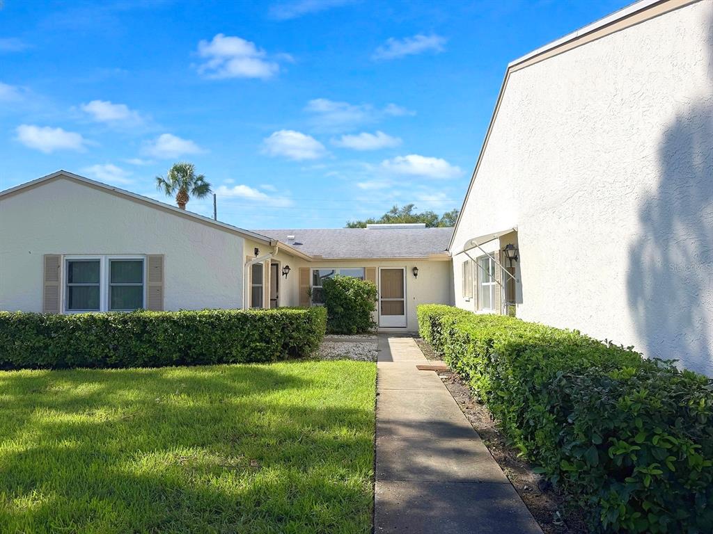 A concrete walkway leads to the front entrance of a single-story home with hedges — 3386 39TH STREET S UNIT B, ST PETERSBURG, FL
