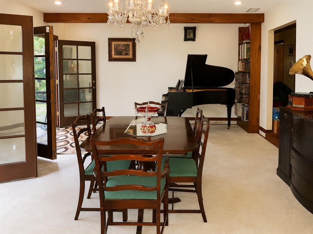 A dining room features a wooden table, green chairs, a grand piano, and French doors — 2234 W MAPLE TERRACE, ST CLOUD, FL
