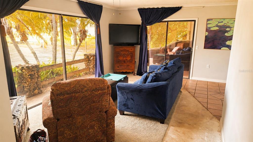 A living room features a blue sofa, a patterned armchair, and sliding glass doors — 2234 W MAPLE TERRACE, ST CLOUD, FL