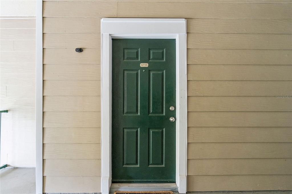 A dark green front door with the number 1035 is set in tan horizontal siding — 13015 PLANTATION PARK CIRCLE UNIT 1035, ORLANDO, FL