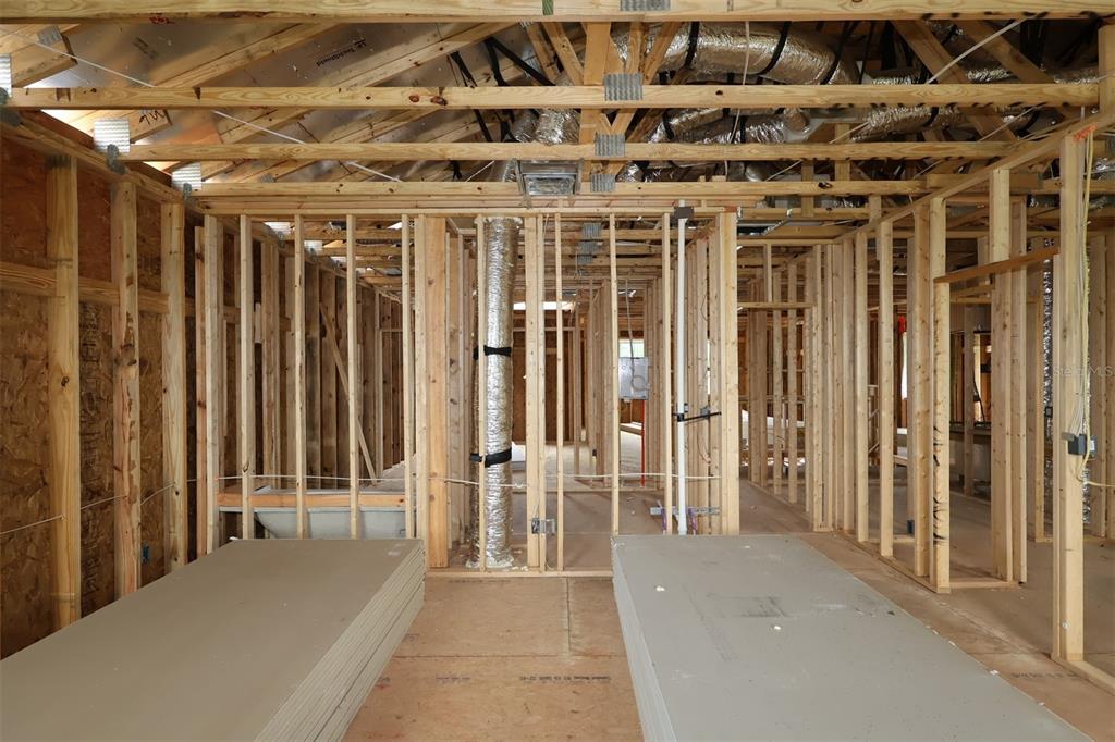 An interior view of a house under construction showing wooden wall framing and drywall stacks — 6759 YELLOW WARBLER BEND, ST CLOUD, FL
