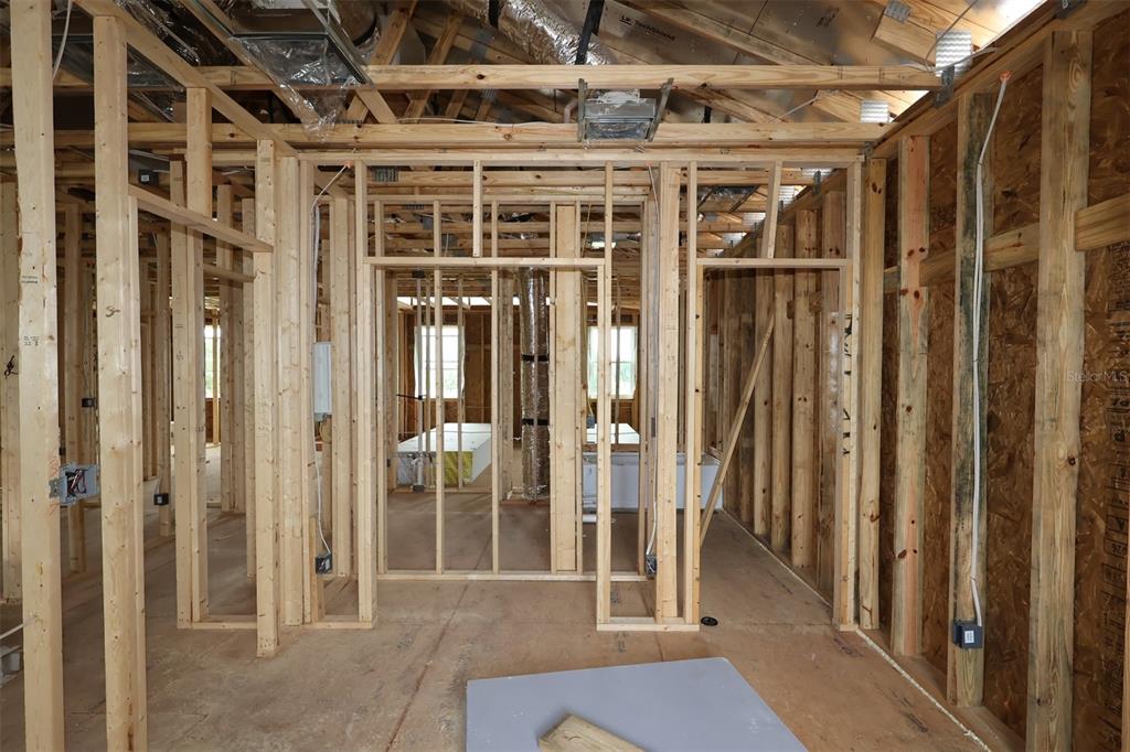 Interior view of a house under construction showing wood framing, wall studs, and exposed ceiling trusses — 6759 YELLOW WARBLER BEND, ST CLOUD, FL