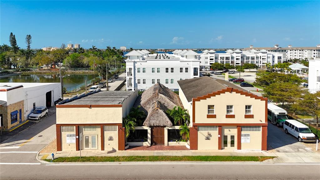 An aerial view shows three adjacent commercial buildings with a thatched-roof structure in the center — 1001 & 1007 MANATEE AVENUE E, BRADENTON, FL