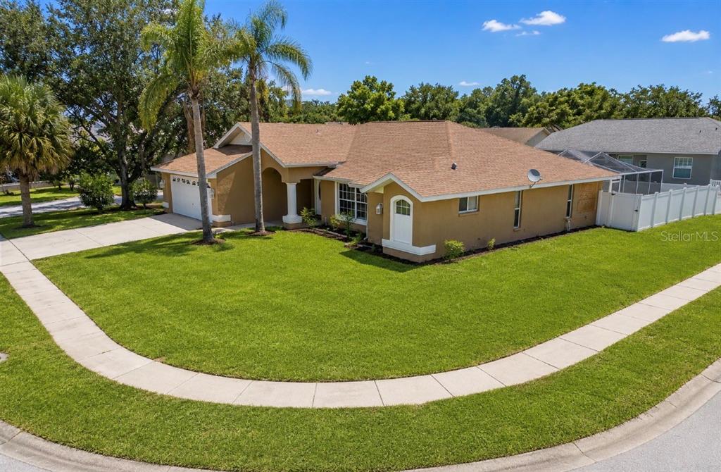 A tan single-story house with a brown shingled roof sits on a corner lot — 10149 BRIAR CIRCLE, HUDSON, FL