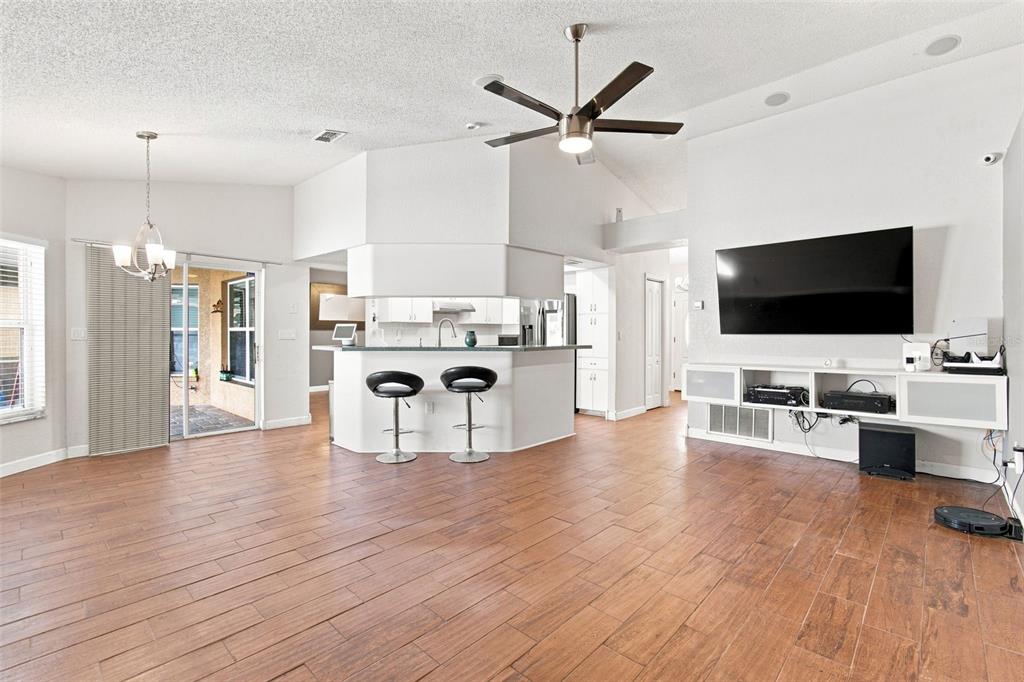 A living room with wood-look tile flooring, a ceiling fan, and a breakfast bar — 10149 BRIAR CIRCLE, HUDSON, FL