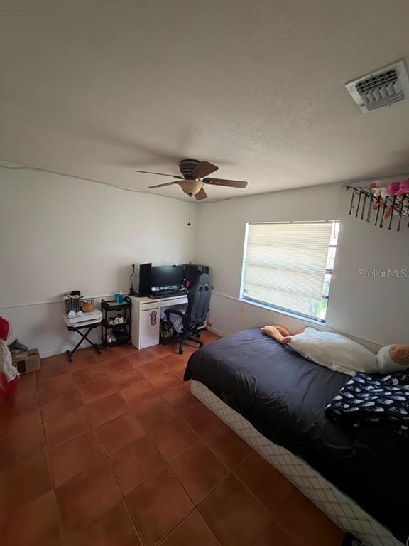 A bedroom features tile flooring, a ceiling fan, a desk setup, and a bed — 2207 CARIBBEAN DRIVE, KISSIMMEE, FL