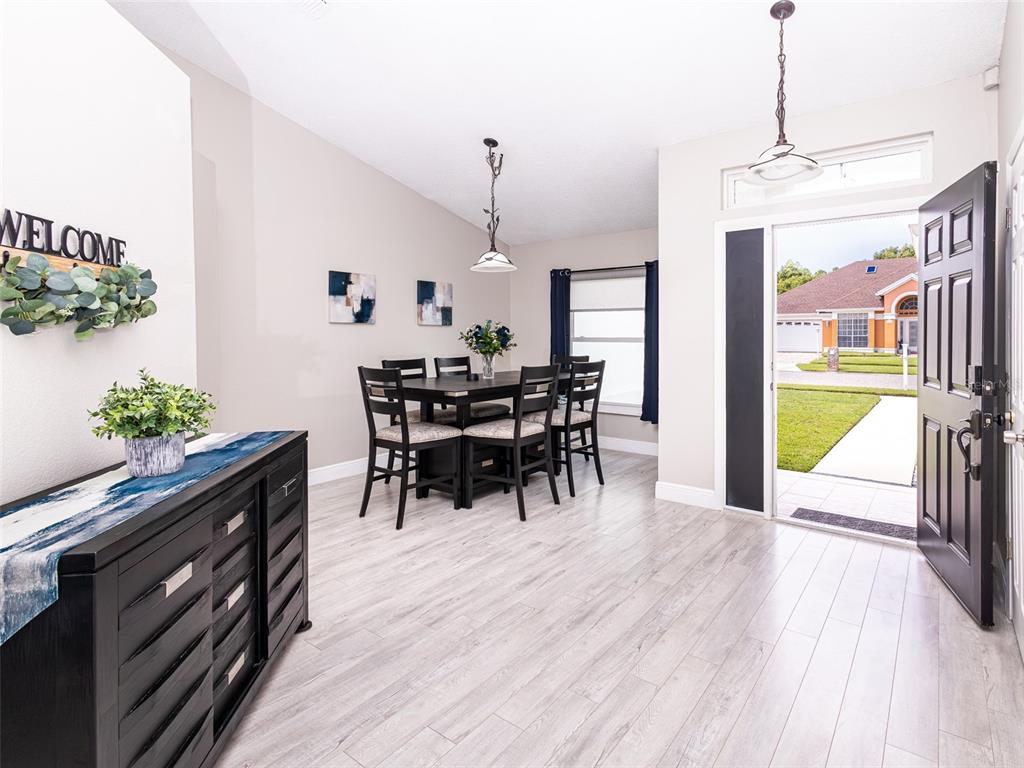 A dining area features light wood-look flooring, a dark wood table set, and an open door — 2540 ROLLING BROAK DRIVE, ORLANDO, FL