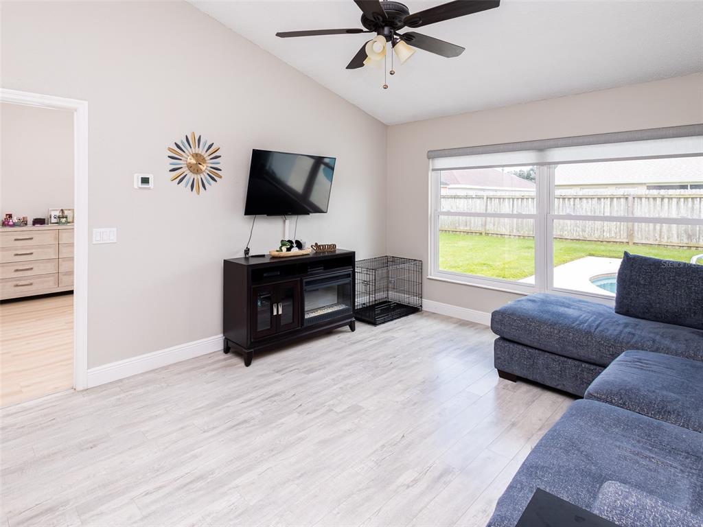 A living room features light wood-look flooring, a wall-mounted television, a fireplace console, and a sectional — 2540 ROLLING BROAK DRIVE, ORLANDO, FL