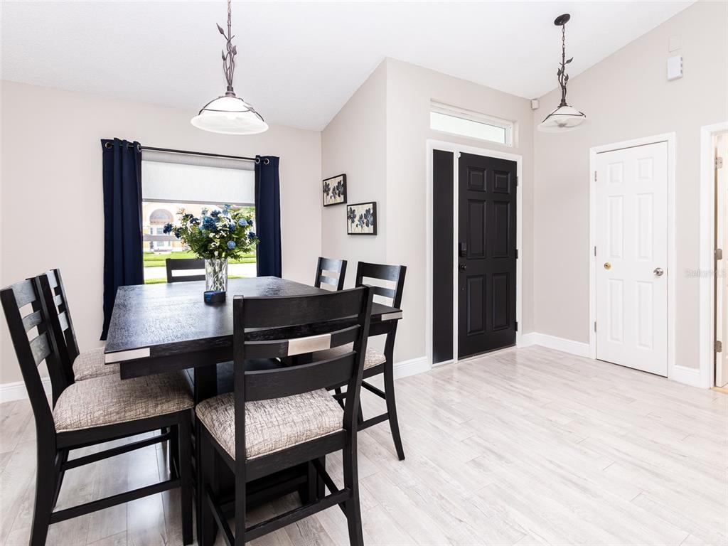 A dining room features a dark wood table, matching chairs, and a black front door — 2540 ROLLING BROAK DRIVE, ORLANDO, FL