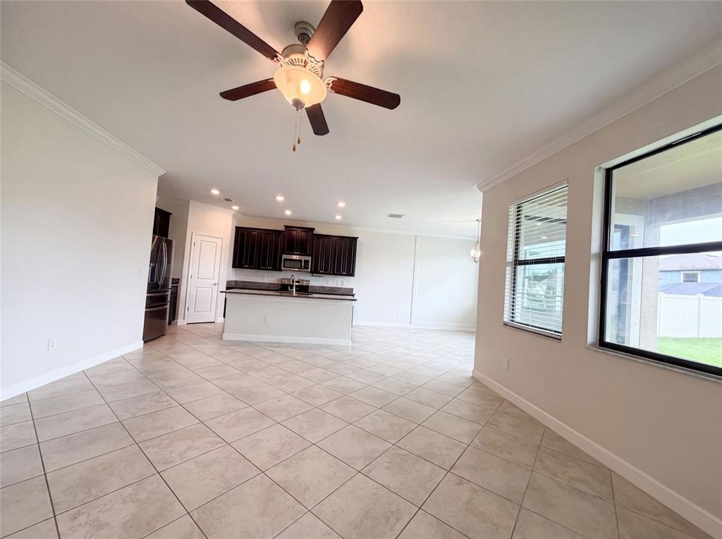 An open-concept kitchen and living area features tile flooring, dark cabinetry, and a ceiling fan — 9709 IVORY DRIVE, RUSKIN, FL