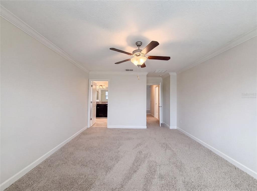 A carpeted bedroom features a ceiling fan and two doorways leading to other rooms — 9709 IVORY DRIVE, RUSKIN, FL