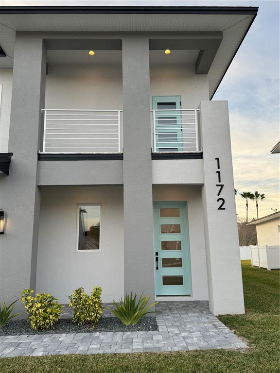 A two-story modern house exterior features gray stucco walls, light blue doors, and white railings — 1172 WINDJAMMER DRIVE, LAKELAND, FL