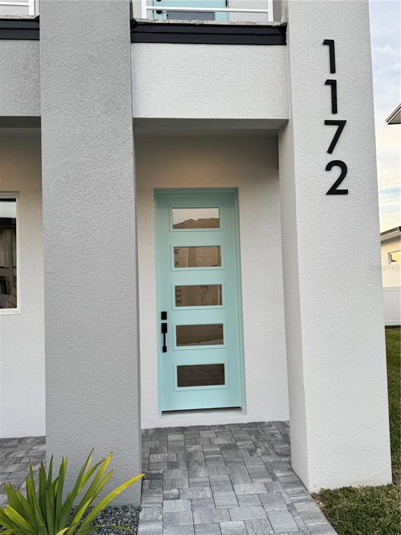 A modern home exterior features a light blue front door with five glass panels — 1172 WINDJAMMER DRIVE, LAKELAND, FL