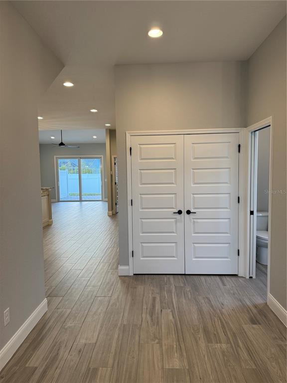 A hallway with wood-look tile flooring leads to a living area with sliding glass doors — 1172 WINDJAMMER DRIVE, LAKELAND, FL