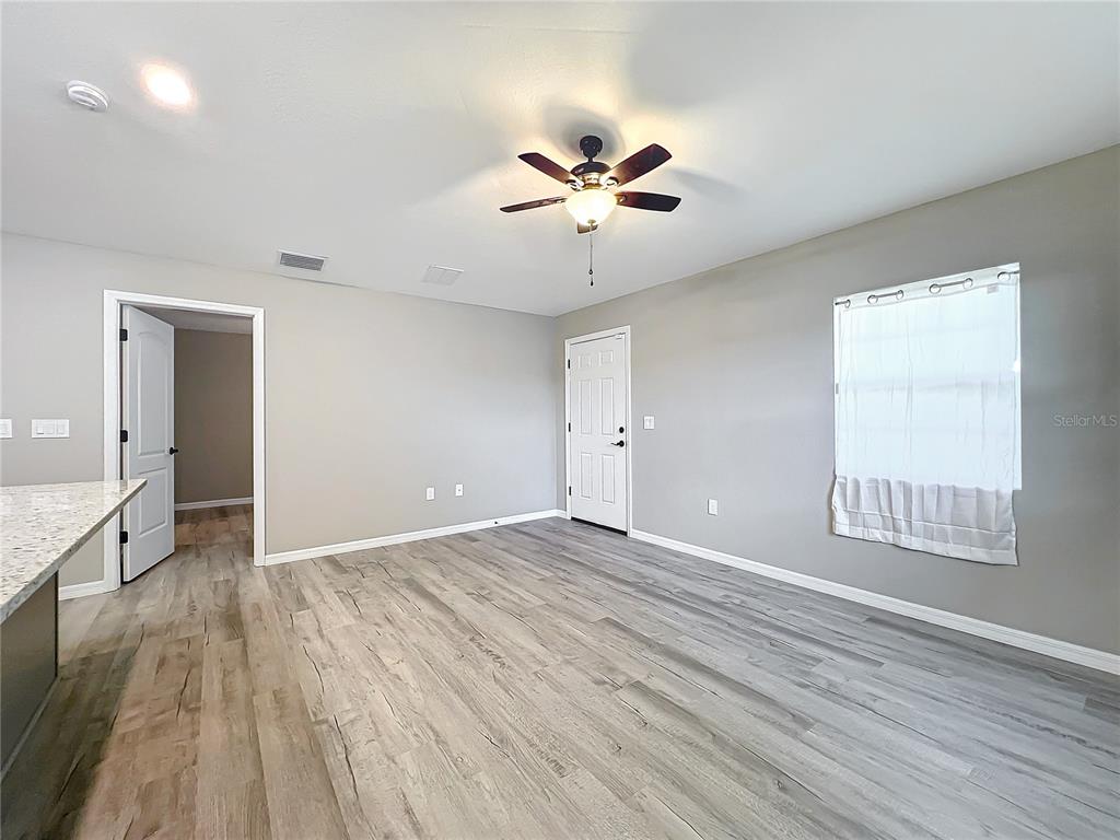 An interior room features light gray walls, wood-look flooring, a ceiling fan, and two doors — 7091 TAMARIND WAY, LAKE WALES, FL