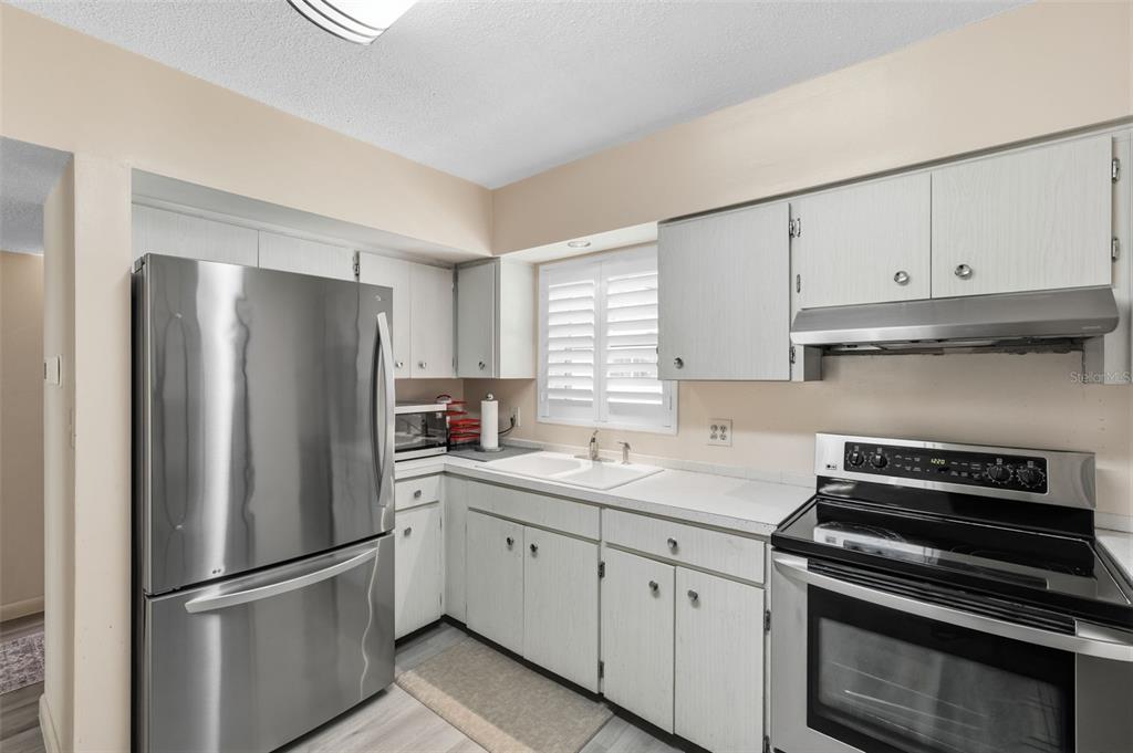 A kitchen with white cabinets, stainless steel appliances, and a white countertop and sink — 9940 47TH AVENUE N UNIT 216, ST PETERSBURG, FL