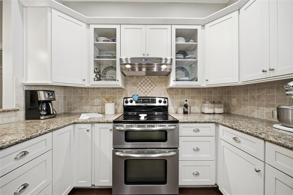 A kitchen features white cabinets, granite countertops, a stainless steel oven, and a tiled backsplash — 1905 PINE STREET, VALRICO, FL